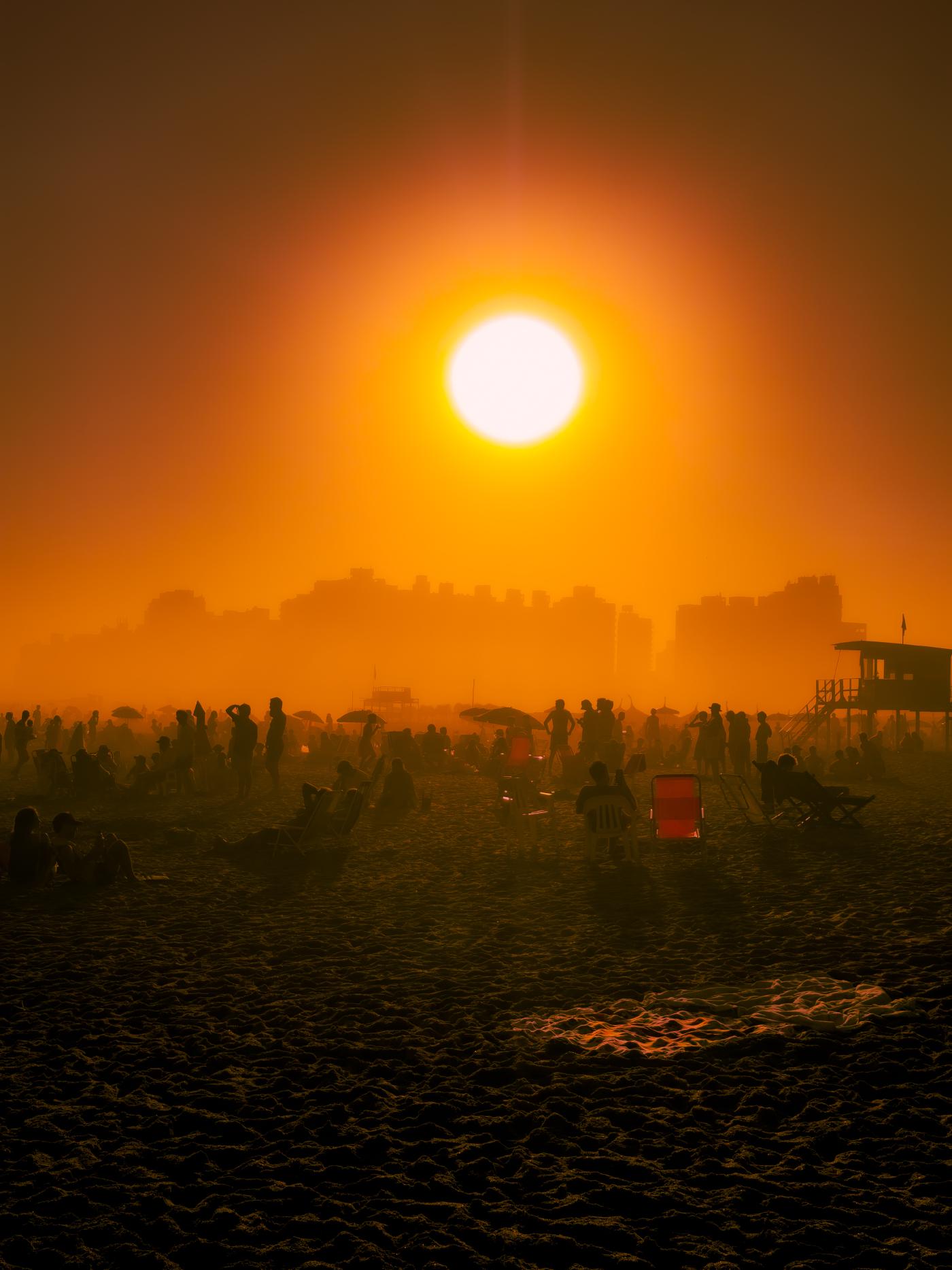 A diptych made of two images of people and umbrellas on the beach, now in full ominous color