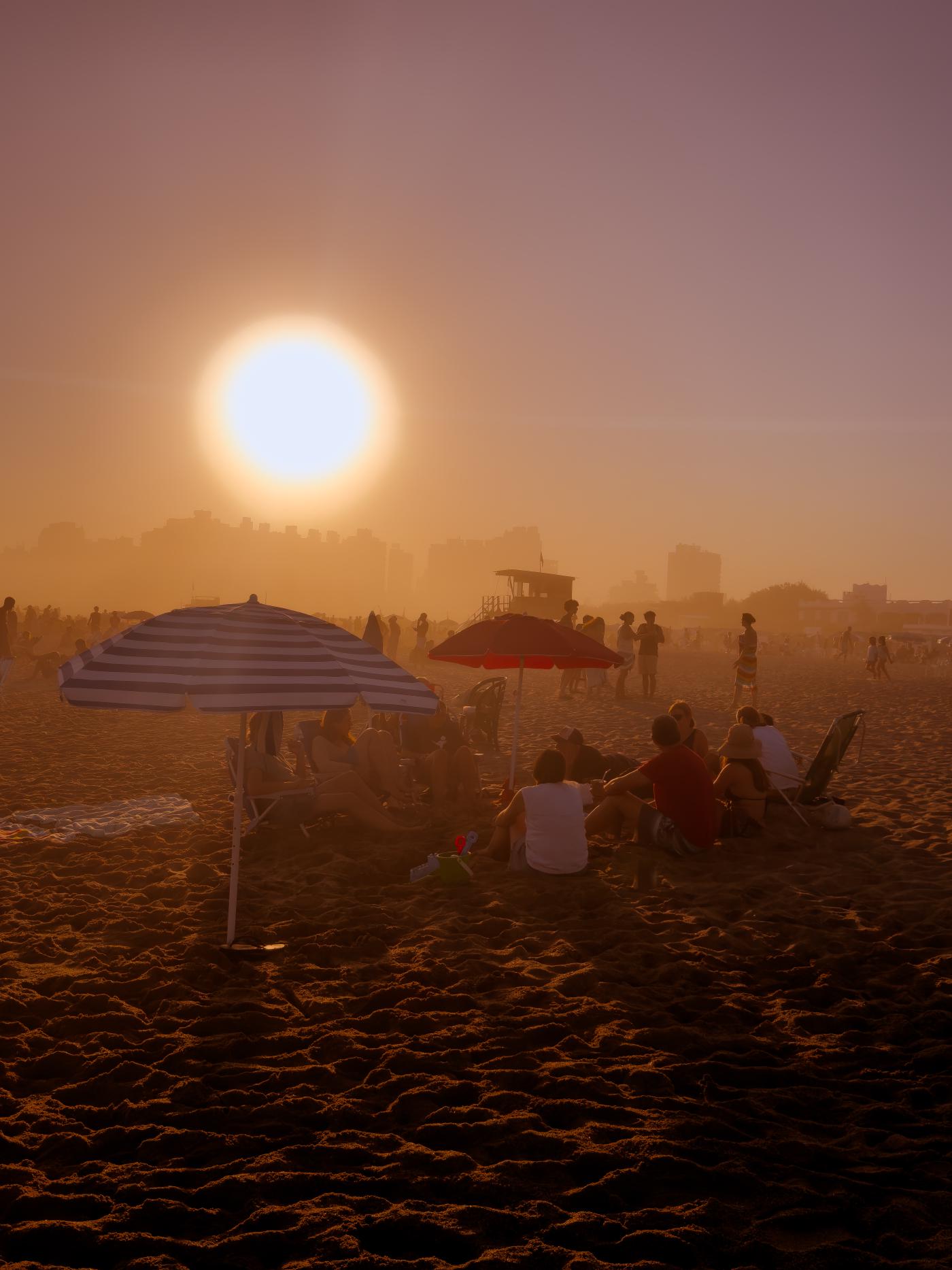 A diptych made of two images of people and umbrellas on the beach, now in full ominous color
